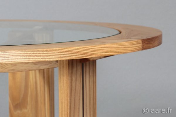 Vue de profil du plateau rond en verre et bois de la table basse Arceau en orme massif